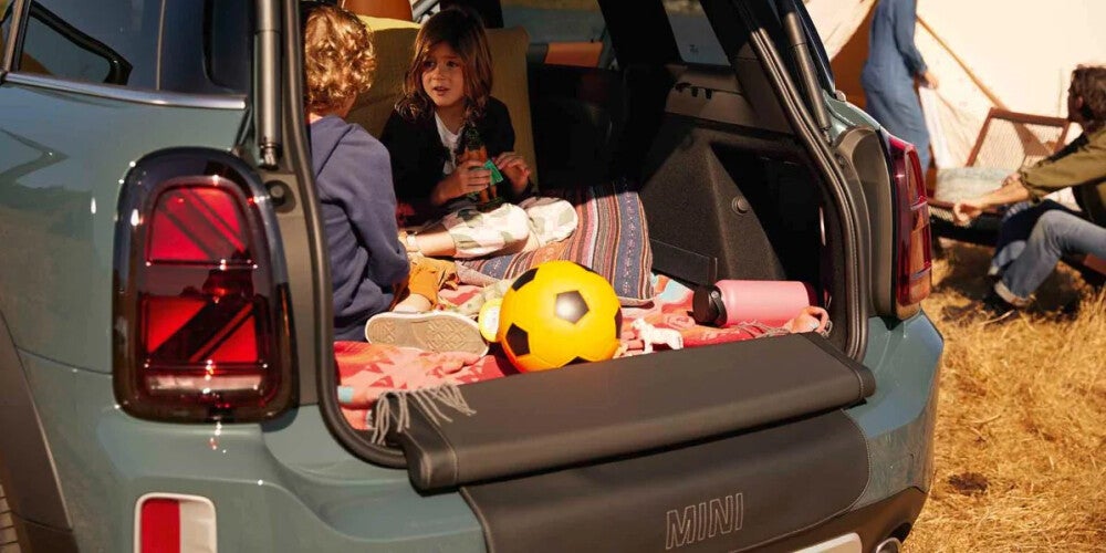 2022 MINI Cooper Countryman cargo space with kids in cargo space and parents pitching tent in the background