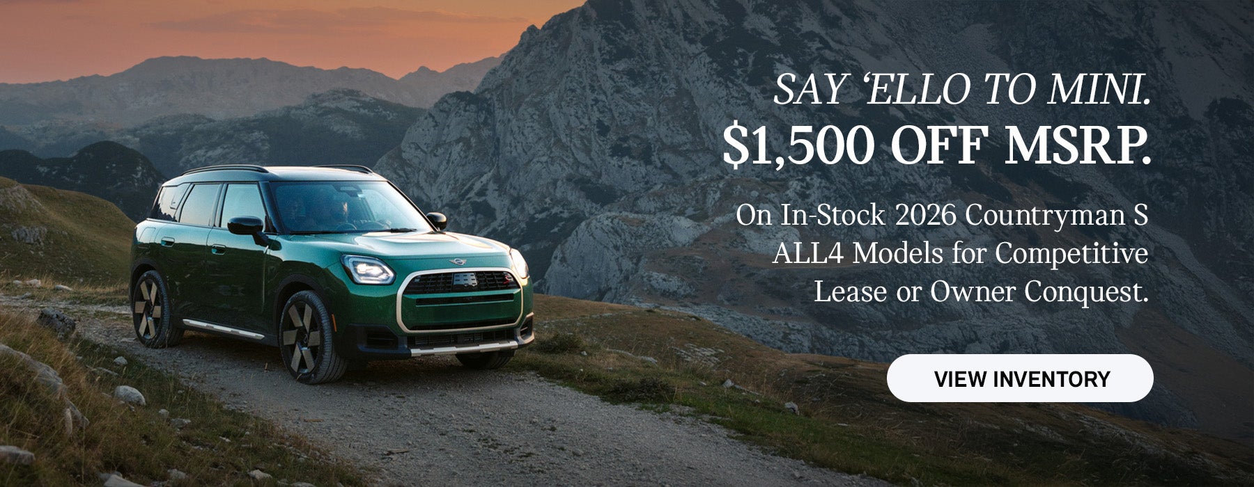 Front passenger side view of a MINI Countryman driving on a mountainous road.