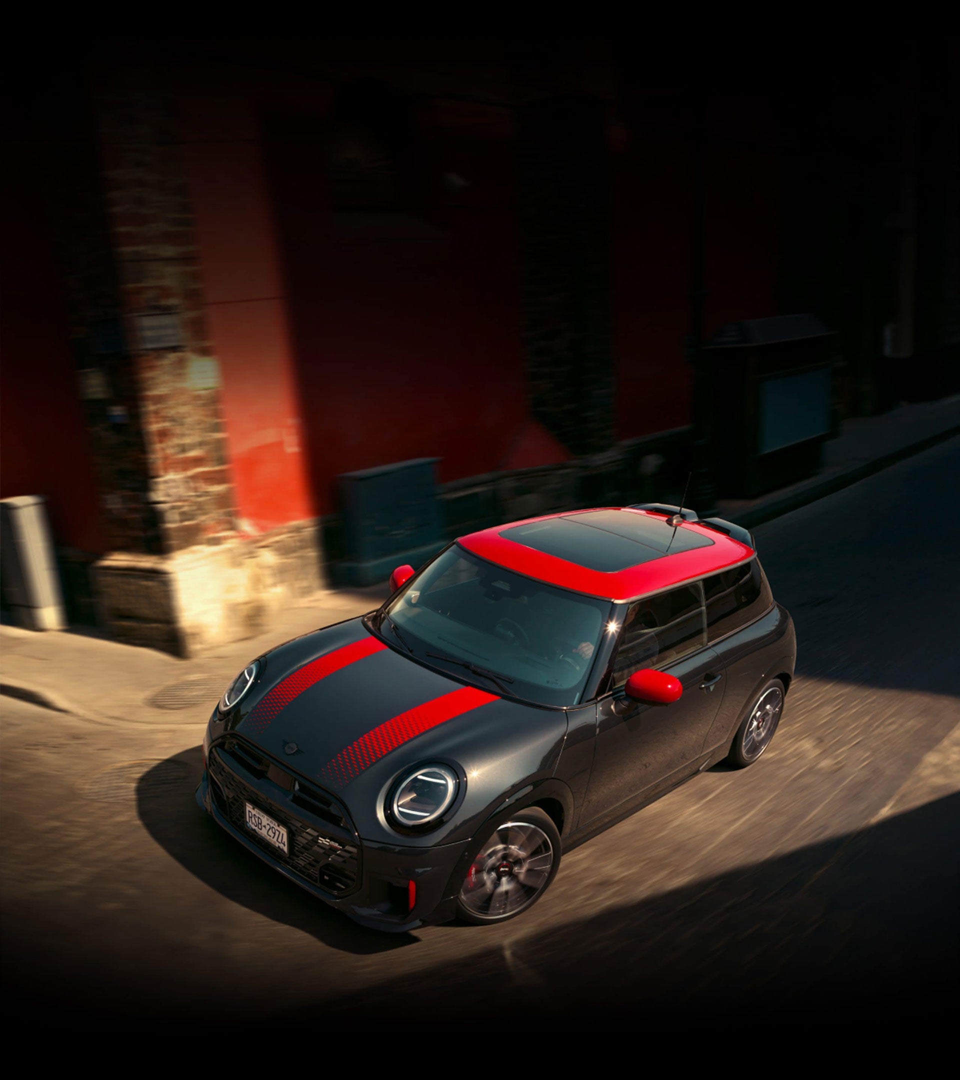 Bird’s-eye view of the MINI JCW 2 Door turning a corner on a cobblestone street.