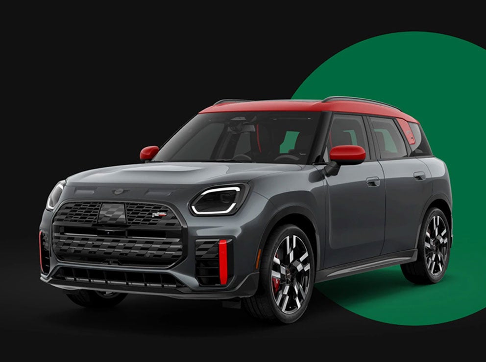 Angled front-to-rear view of the MINI JCW Countryman ALL4 in front of a green circle with a black background.