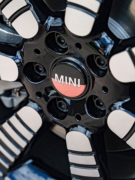 Closeup view of a light-alloy wheel and wheel cap with MINI branding on it.