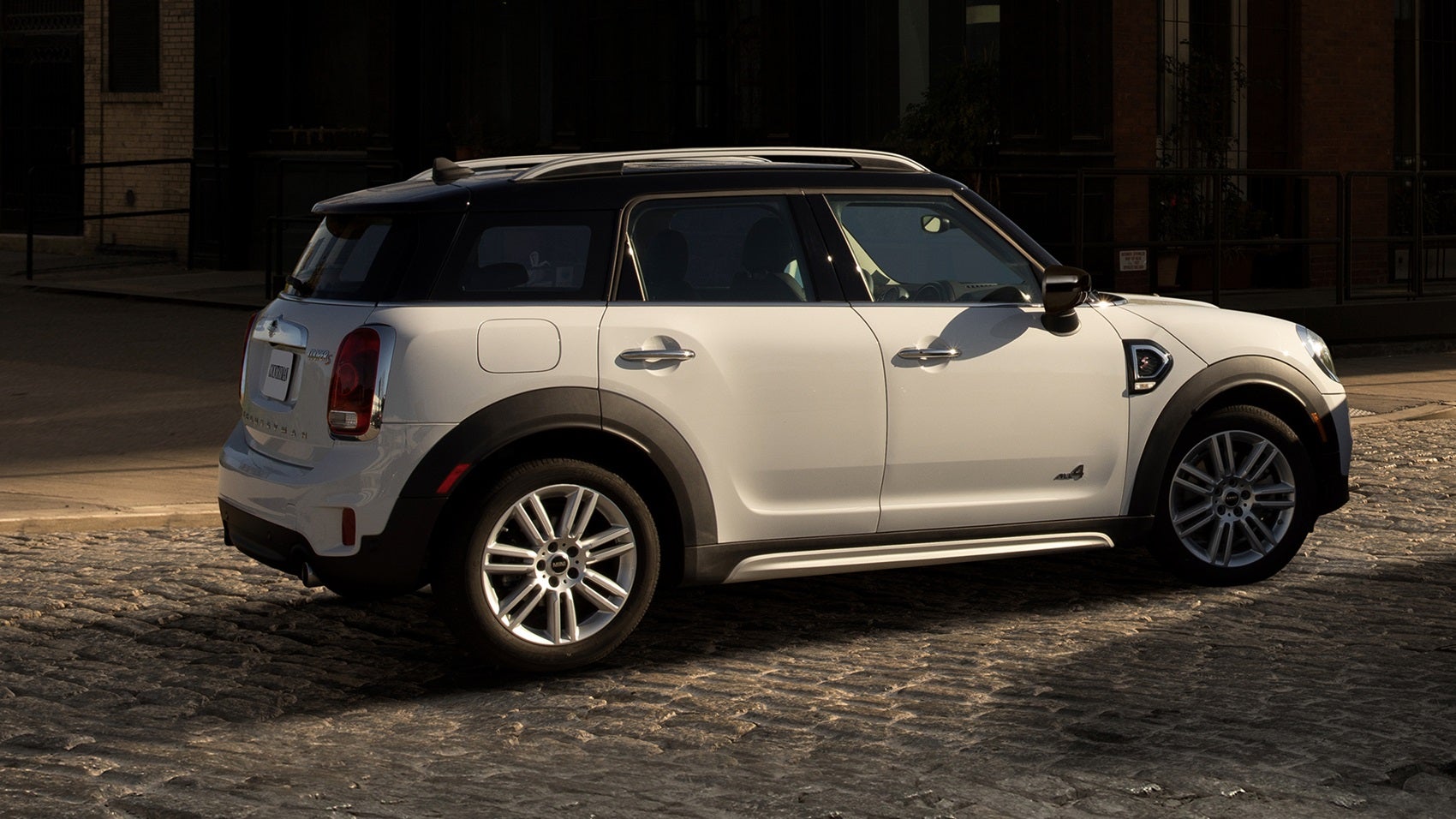 A white MINI Countryman on a cobblestone pathway in a historic downtown setting